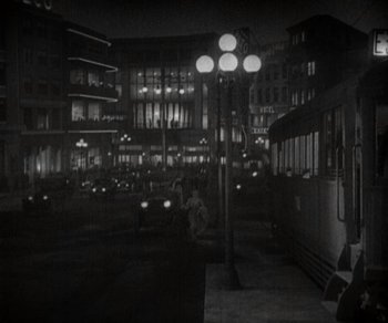 Movie still from “Sunrise” (1927), directed by F.W. Murnau – A black - and - white photo of a city street at night; Extreme Wide shot, High angle