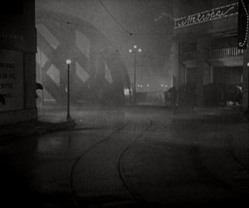 Movie still from “Sunrise” (1927), directed by F.W. Murnau – A black - and - white photo of a city street at night; Extreme Wide shot, High angle