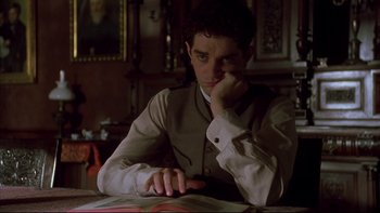 Movie still from “Sunshine” (1999), directed by István Szabó – A man sitting at a table with his hand under his chin; Medium shot, High angle