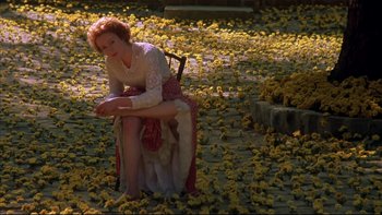 Movie still from “Sunshine” (1999), directed by István Szabó – A woman sitting on a chair in the middle of a field of yellow flowers; Wide shot, High angle