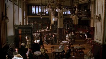 Movie still from “Sunshine” (1999), directed by István Szabó – People are sitting at tables in an old - fashioned restaurant; Extreme Wide shot, High angle
