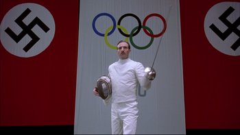 Movie still from “Sunshine” (1999), directed by István Szabó – A fencer holding a sword in front of the olympic rings; Medium shot, Low angle
