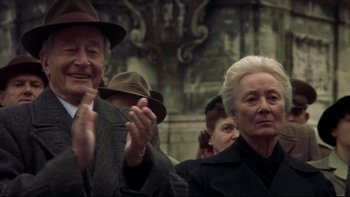 Movie still from “Sunshine” (1999), directed by István Szabó – An older man and woman clapping in a crowd of onlookers; Medium shot, Low angle