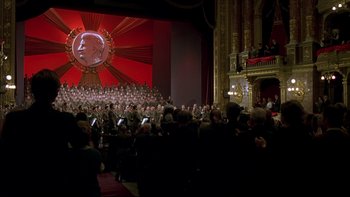 Movie still from “Sunshine” (1999), directed by István Szabó – A large group of people are gathered in front of a stage; Extreme Wide shot, High angle