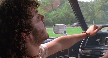 Movie still from “Super Troopers” (2001), directed by Jay Chandrasekhar – A young man driving a car in the middle of the day; Close Up shot, Low angle