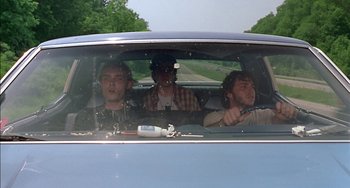 Movie still from “Super Troopers” (2001), directed by Jay Chandrasekhar – Three men in the back seat of a blue car; Medium shot, Low angle