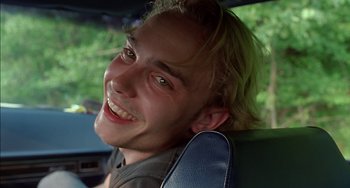 Movie still from “Super Troopers” (2001), directed by Jay Chandrasekhar – A young man smiling while sitting in the back of a car; Close Up shot, Low angle