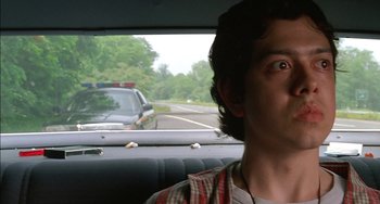 Movie still from “Super Troopers” (2001), directed by Jay Chandrasekhar – A man sitting in the back seat of a car looking out the window; Close Up shot, Low angle