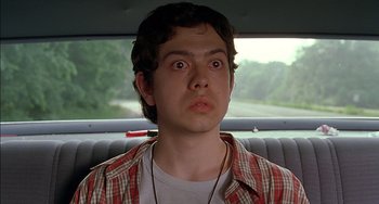 Movie still from “Super Troopers” (2001), directed by Jay Chandrasekhar – A young man in plaid shirt sitting in the back seat of a car; Close Up shot, Low angle