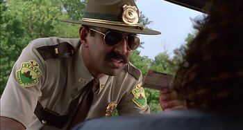 Movie still from “Super Troopers” (2001), directed by Jay Chandrasekhar – A man in a hat and sunglasses is holding a ticket; Close Up shot, Over the shoulder angle