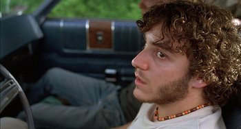 Movie still from “Super Troopers” (2001), directed by Jay Chandrasekhar – A young man sitting in the back seat of a car; Close Up shot, Low angle