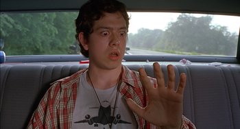 Movie still from “Super Troopers” (2001), directed by Jay Chandrasekhar – A young man in the back seat of a car with his hand up; Close Up shot, Low angle