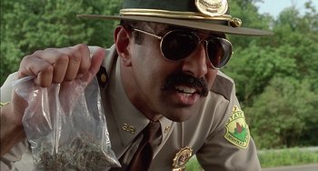 Movie still from “Super Troopers” (2001), directed by Jay Chandrasekhar – A man in a hat and sunglasses holding a bag of marijuana; Close Up shot, Low angle