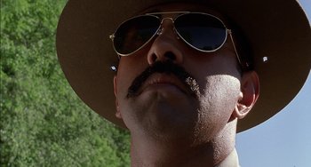 Movie still from “Super Troopers” (2001), directed by Jay Chandrasekhar – A person wearing a hat and sunglasses; Close Up shot, Low angle
