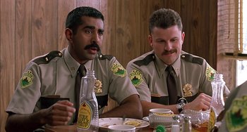 Movie still from “Super Troopers” (2001), directed by Jay Chandrasekhar – A couple of men sitting next to each other at a table; Close Up shot, Low angle
