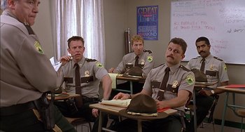 Movie still from “Super Troopers” (2001), directed by Jay Chandrasekhar – A group of men sitting at a desk in a classroom; Medium shot, Over the shoulder angle