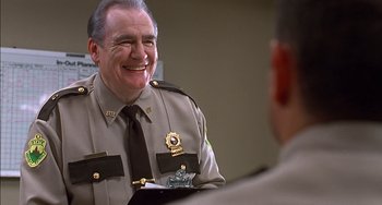 Movie still from “Super Troopers” (2001), directed by Jay Chandrasekhar – A man in a uniform sitting next to another man in a suit; Close Up shot, Over the shoulder angle