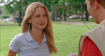Movie still from “Super Troopers” (2001), directed by Jay Chandrasekhar – A young woman is smiling while standing in a park; Close Up shot, Over the shoulder angle