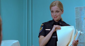 Movie still from “Super Troopers” (2001), directed by Jay Chandrasekhar – A woman in a police uniform holding a piece of paper; Close Up shot, Over the shoulder angle