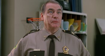 Movie still from “Super Troopers” (2001), directed by Jay Chandrasekhar – A man in a police uniform looking up at the camera; Close Up shot, Low angle