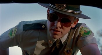 Movie still from “Super Troopers” (2001), directed by Jay Chandrasekhar – A man in a police uniform and sunglasses; Close Up shot, Low angle