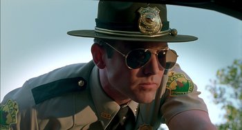 Movie still from “Super Troopers” (2001), directed by Jay Chandrasekhar – A man in a hat and sunglasses is sitting in a car; Close Up shot, Low angle