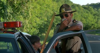 Movie still from “Super Troopers” (2001), directed by Jay Chandrasekhar – A police officer and a child in the back of a car; Medium shot, Over the shoulder angle