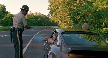 Movie still from “Super Troopers” (2001), directed by Jay Chandrasekhar – A person in the driver's seat of a silver car; Medium shot, Over the shoulder angle
