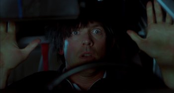 Movie still from “Super Troopers” (2001), directed by Jay Chandrasekhar – A man in a black shirt is in a car looking at the camera; Close Up shot, Low angle