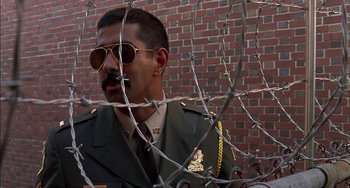 Movie still from “Super Troopers” (2001), directed by Jay Chandrasekhar – A man in a military uniform standing next to barbed wire; Close Up shot, Low angle