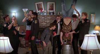 Movie still from “Super Troopers” (2001), directed by Jay Chandrasekhar – A group of people standing in a living room; Wide shot, Low angle