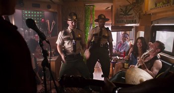 Movie still from “Super Troopers 2” (2018), directed by Jay Chandrasekhar – A couple of men standing next to each other in a room; Wide shot, Low angle