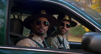 Movie still from “Super Troopers 2” (2018), directed by Jay Chandrasekhar – A couple of men sitting in the back of a car; Medium shot, Over the shoulder angle