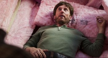 Movie still from “Super Troopers 2” (2018), directed by Jay Chandrasekhar – A man laying on a bed with pink pillows; Close Up shot, Overhead angle