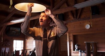 Movie still from “Super Troopers 2” (2018), directed by Jay Chandrasekhar – A man in a uniform is holding a light; Medium shot, Low angle