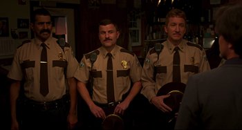 Movie still from “Super Troopers 2” (2018), directed by Jay Chandrasekhar – A group of men in brown police uniforms and ties; Medium shot, Over the shoulder angle