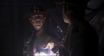 Movie still from “Super Troopers 2” (2018), directed by Jay Chandrasekhar – A man in a uniform is looking into a mirror; Medium shot, Over the shoulder angle