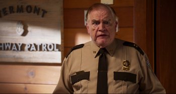 Movie still from “Super Troopers 2” (2018), directed by Jay Chandrasekhar – An older man in a uniform is looking at the camera; Close Up shot, Over the shoulder angle