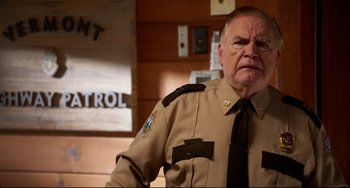 Movie still from “Super Troopers 2” (2018), directed by Jay Chandrasekhar – An older man in a police uniform in front of a patrol sign; Close Up shot, Over the shoulder angle