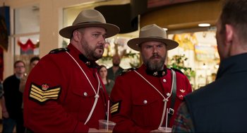 Movie still from “Super Troopers 2” (2018), directed by Jay Chandrasekhar – A couple of men in red jackets and hats holding drinks; Medium shot, Over the shoulder angle