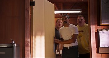Movie still from “Super Troopers 2” (2018), directed by Jay Chandrasekhar – A group of men standing next to each other in a room; Medium shot, Over the shoulder angle