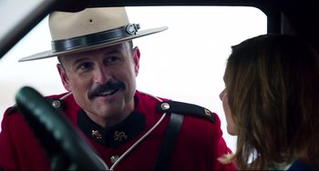 Movie still from “Super Troopers 2” (2018), directed by Jay Chandrasekhar – A man in a red and black uniform talking to a woman in a car; Close Up shot, Over the shoulder angle