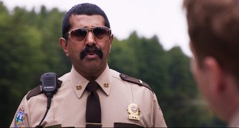 Movie still from “Super Troopers 2” (2018), directed by Jay Chandrasekhar – A man in a police uniform wearing sunglasses; Medium shot, Over the shoulder angle