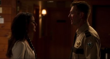 Movie still from “Super Troopers 2” (2018), directed by Jay Chandrasekhar – A man and a woman standing next to each other in a room; Medium shot, Over the shoulder angle