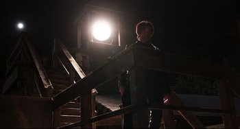 Movie still from “Super Troopers 2” (2018), directed by Jay Chandrasekhar – A man standing on top of a set of stairs at night; Wide shot, Low angle