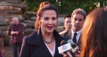 Movie still from “Super Troopers 2” (2018), directed by Jay Chandrasekhar – A woman is holding a microphone while talking to a crowd; Close Up shot, Over the shoulder angle