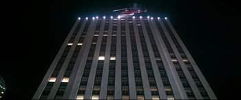 Movie still from “Superman II” (1980), directed by Richard Lester – A helicopter flying over a tall building at night; Extreme Wide shot, Low angle