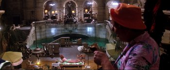 Movie still from “Superman II” (1980), directed by Richard Lester – A man is sitting on a bed in a room with a fountain; Wide shot, High angle