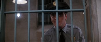 Movie still from “Superman II” (1980), directed by Richard Lester – A man in a uniform behind a fence; Close Up shot, Low angle