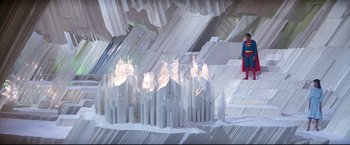 Movie still from “Superman II” (1980), directed by Richard Lester – A man in a superman costume standing next to a building made out of paper; Extreme Wide shot, High angle